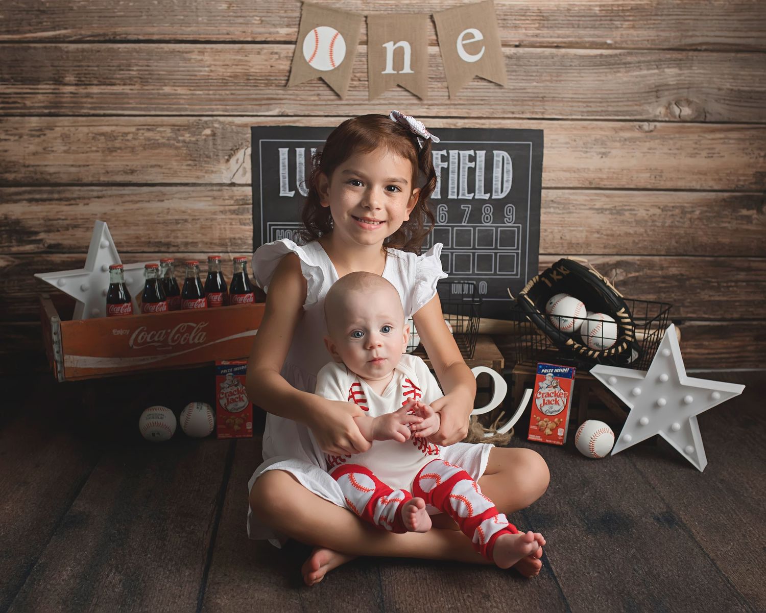 Baseball themed first birthday photo setup with wooden backdrop and sports decor.
