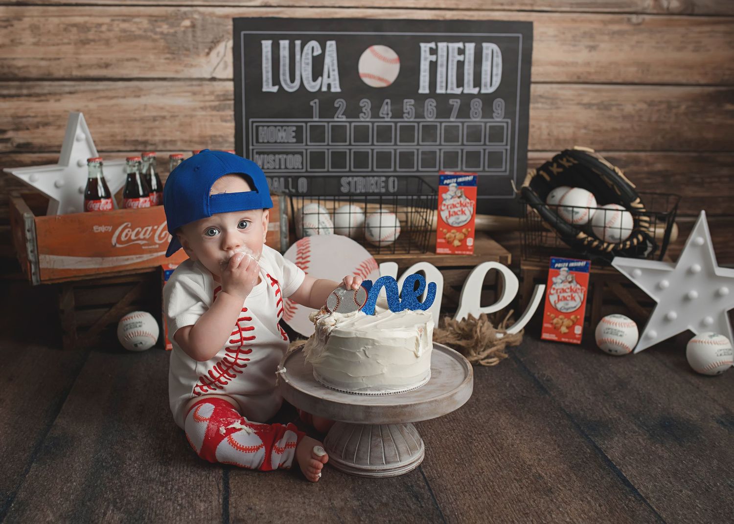 Baseball themed cake smash setup with scoreboard backdrop and vintage sports decorations.