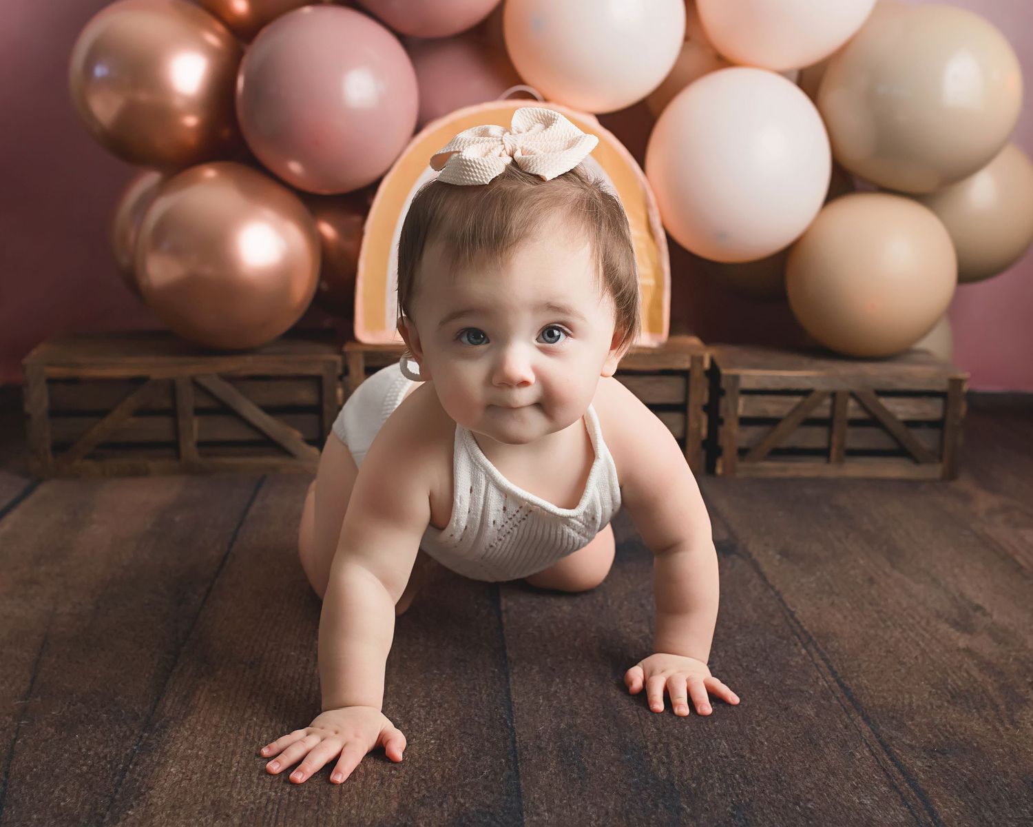 Crawling baby photo with rose gold balloon backdrop.