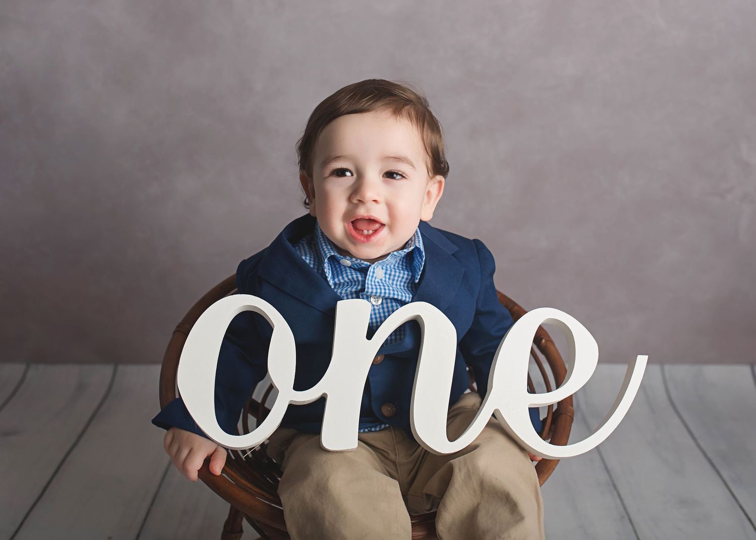 One year milestone photo with toddler holding large white letters.