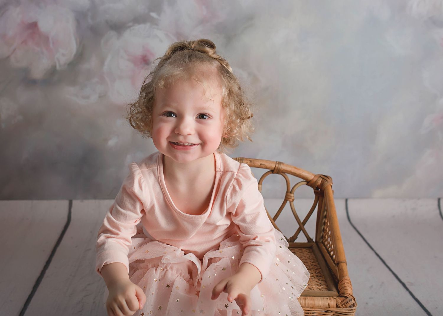 Professional portrait session featuring a pink dress against a dreamy clouded backdrop.