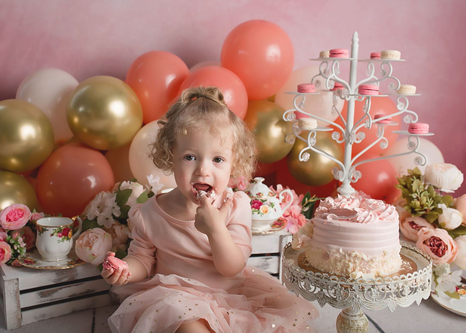 Pink and gold balloon decorations surround a beautiful cake setup for a special celebration.