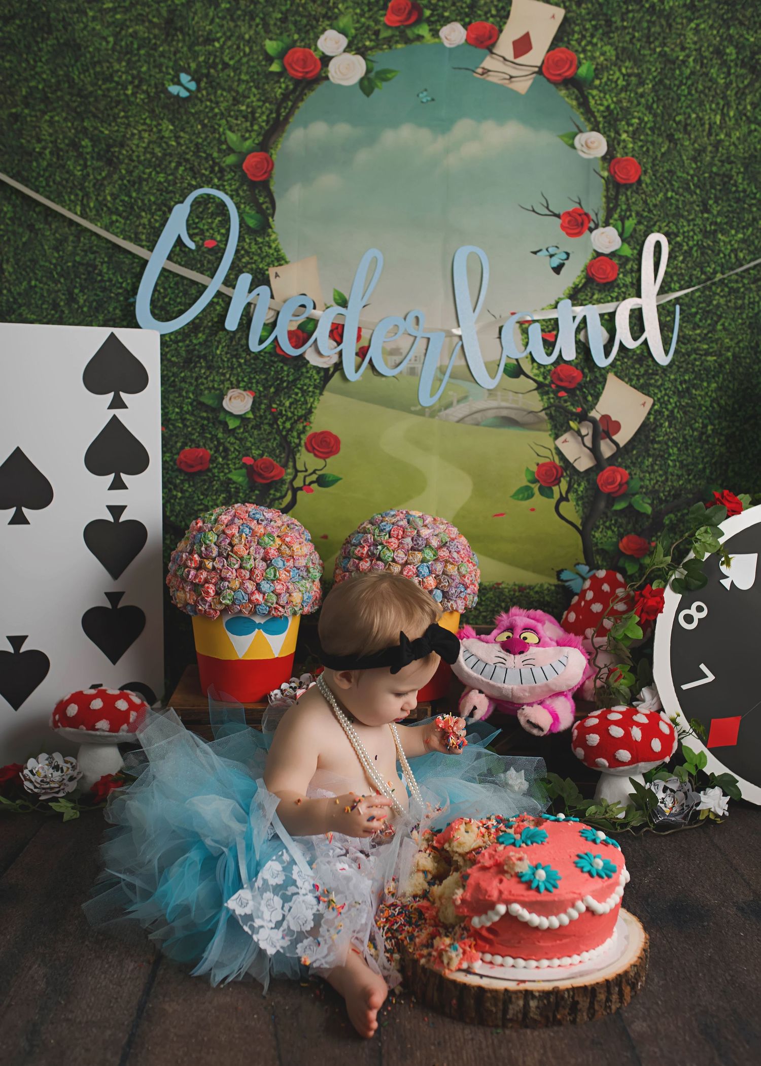 Alice in Wonderland themed cake smash photo setup with playing cards and mushroom decorations.