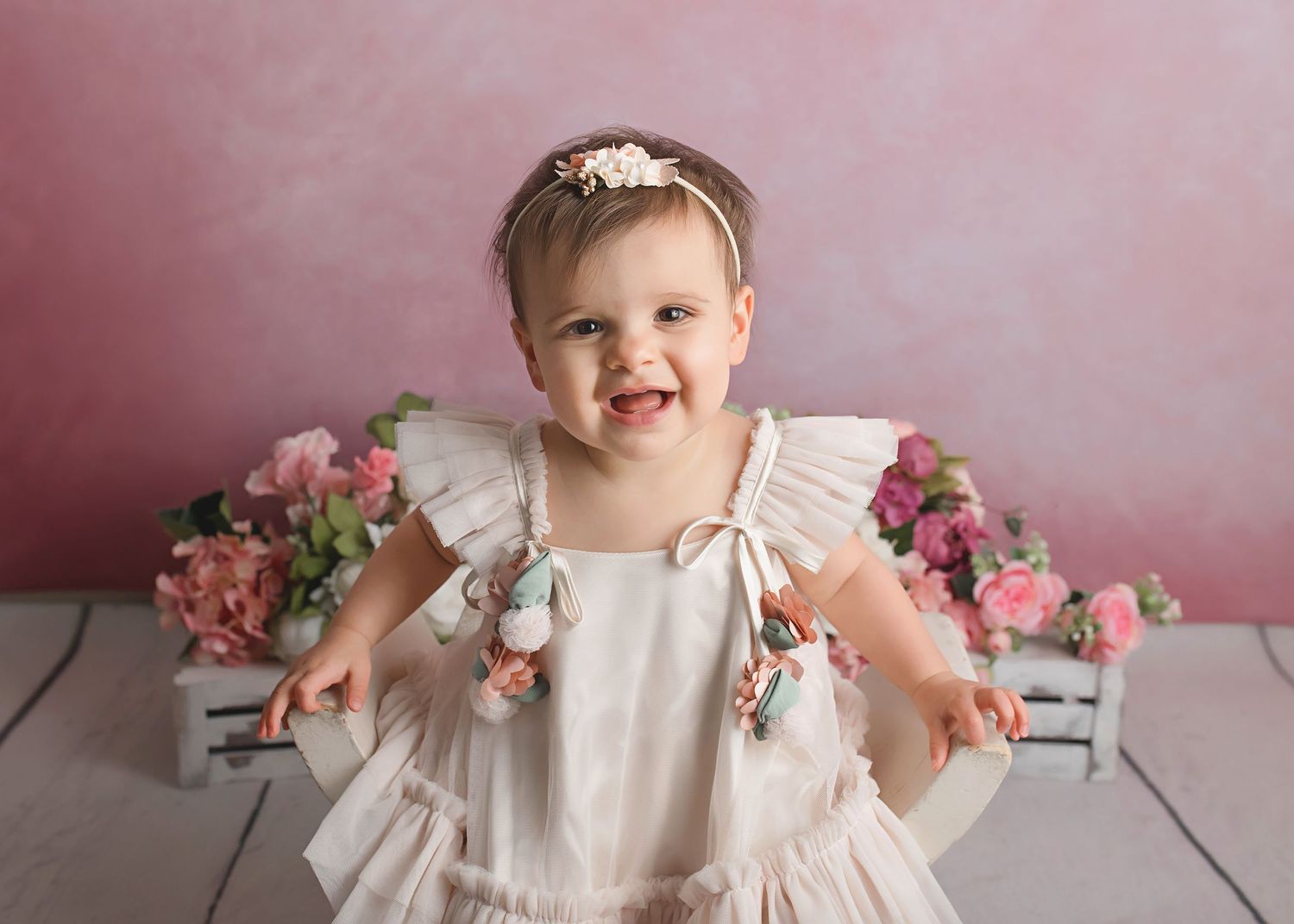 Studio portrait with pink background and white ruffle dress.