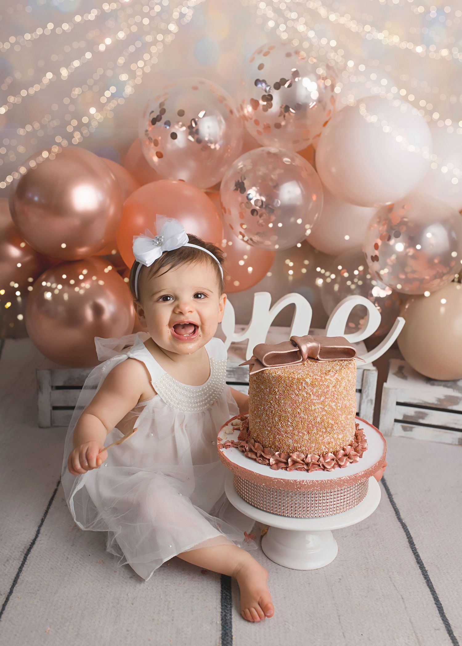 First birthday celebration with sparkly lights and rose gold cake setup.