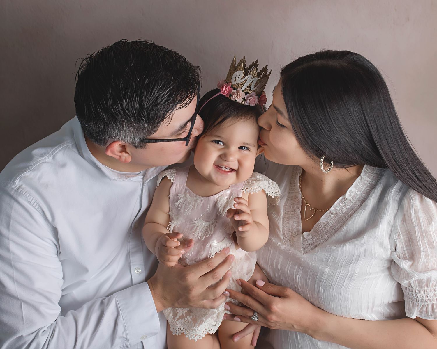Intimate family portrait with parents sharing a tender moment with their baby.