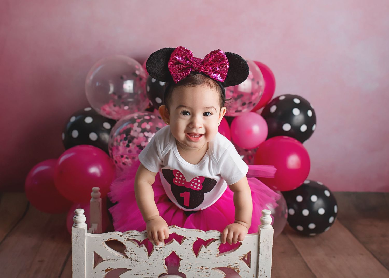 Minnie Mouse inspired birthday photo setup with pink and polka dot balloon arch.
