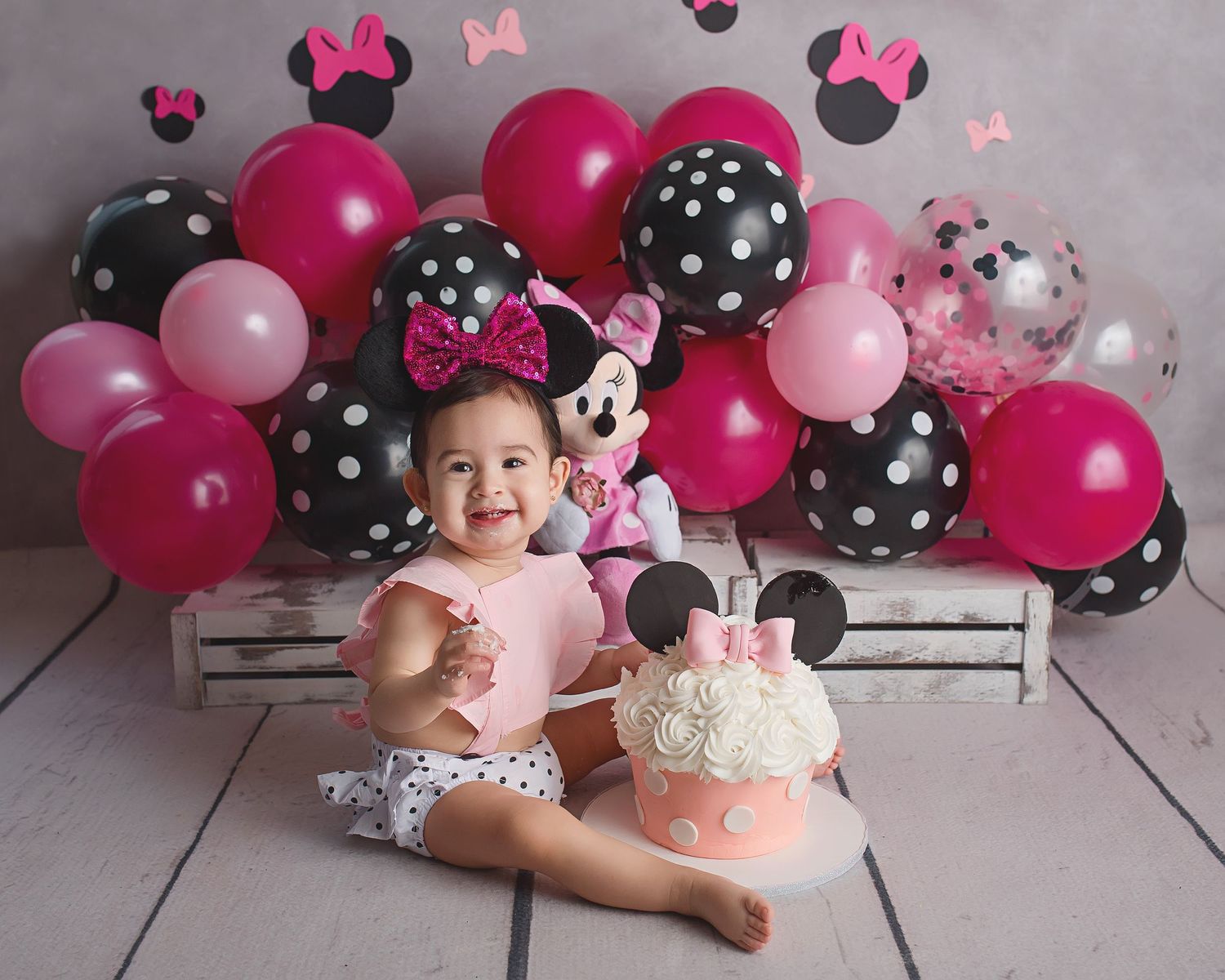 Minnie Mouse themed birthday setup with pink and black polka dot balloons and themed cake.
