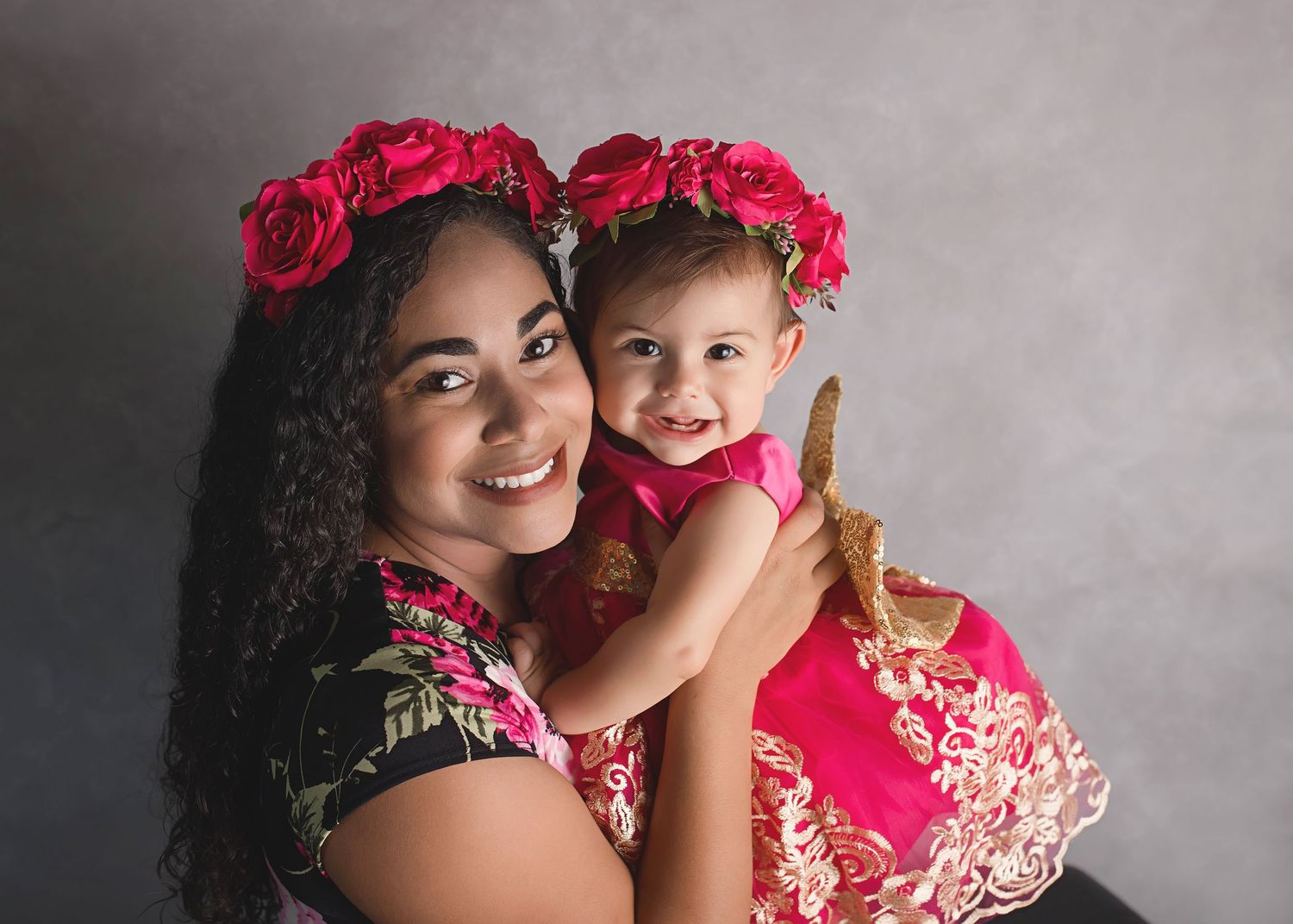 Portrait of two people wearing matching red floral crowns and outfits.