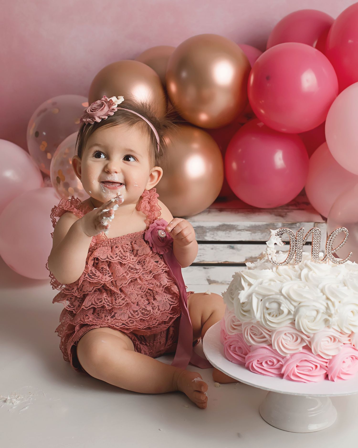 First birthday cake smash with pink and gold balloon arch and rosette cake.