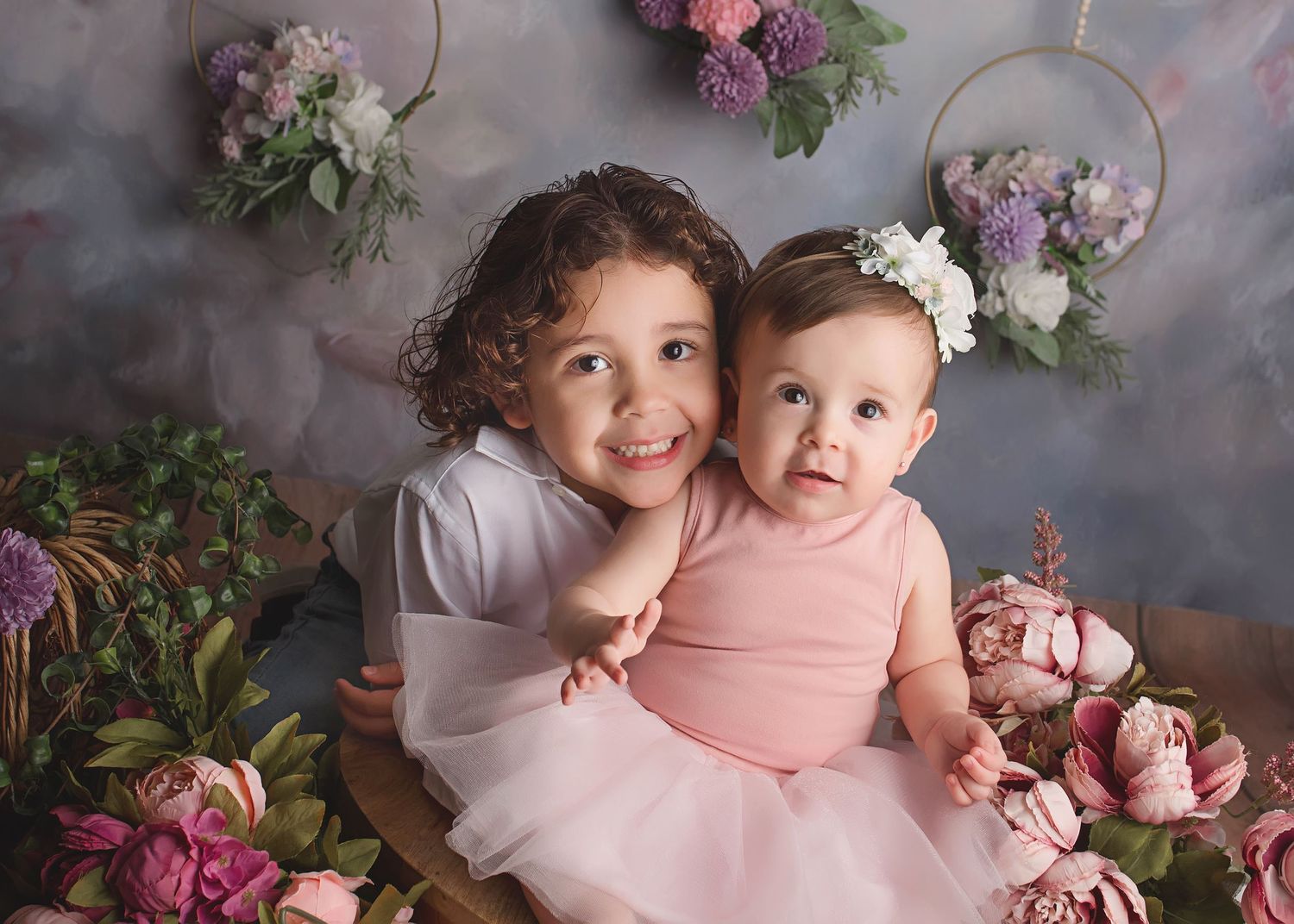 Floral backdrop portrait session with pink and purple flower arrangements.