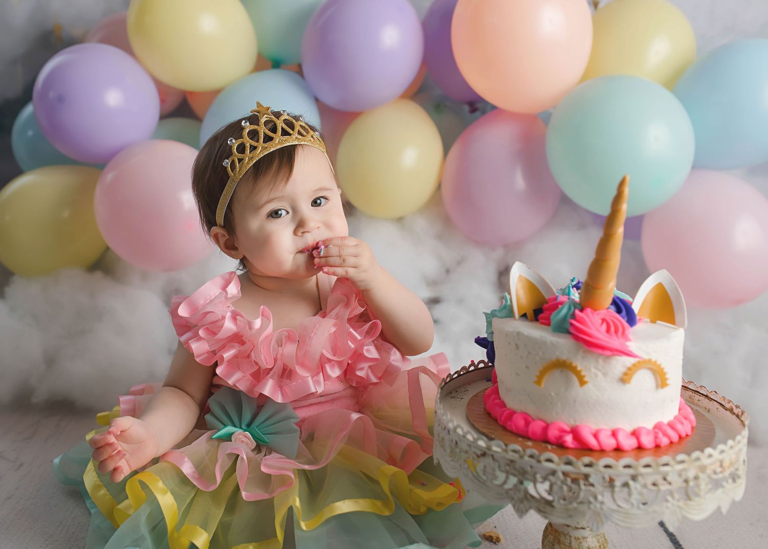 First birthday celebration with unicorn cake and pastel balloon backdrop.