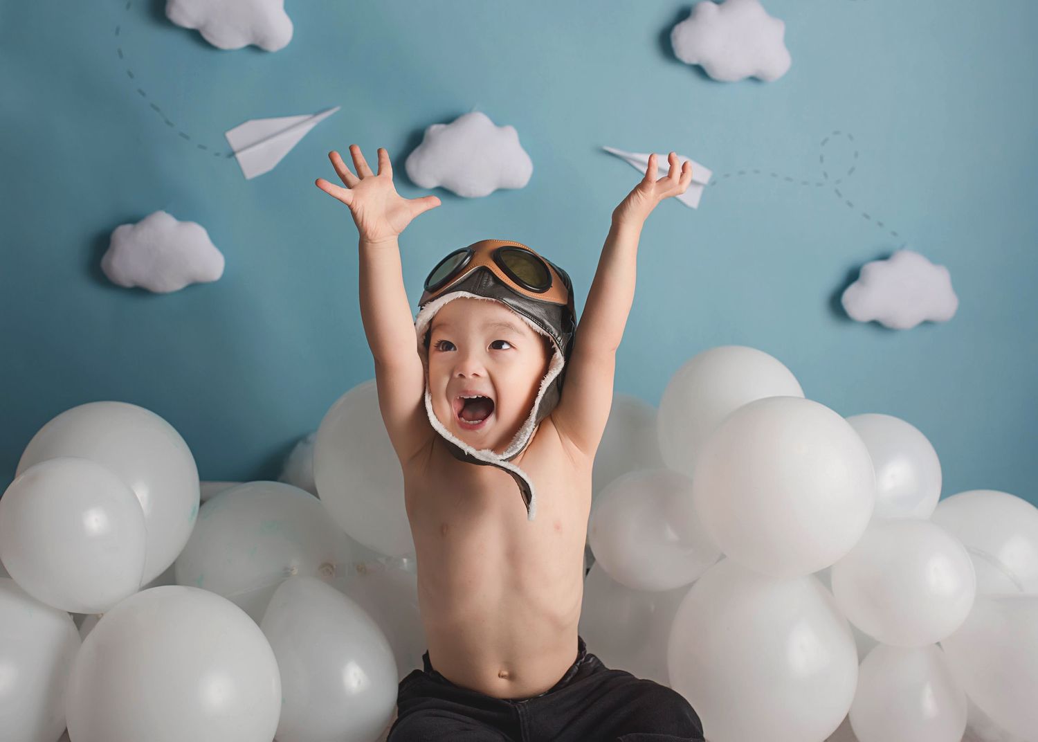 Creative photo with paper airplanes and white cloud decorations against blue background.
