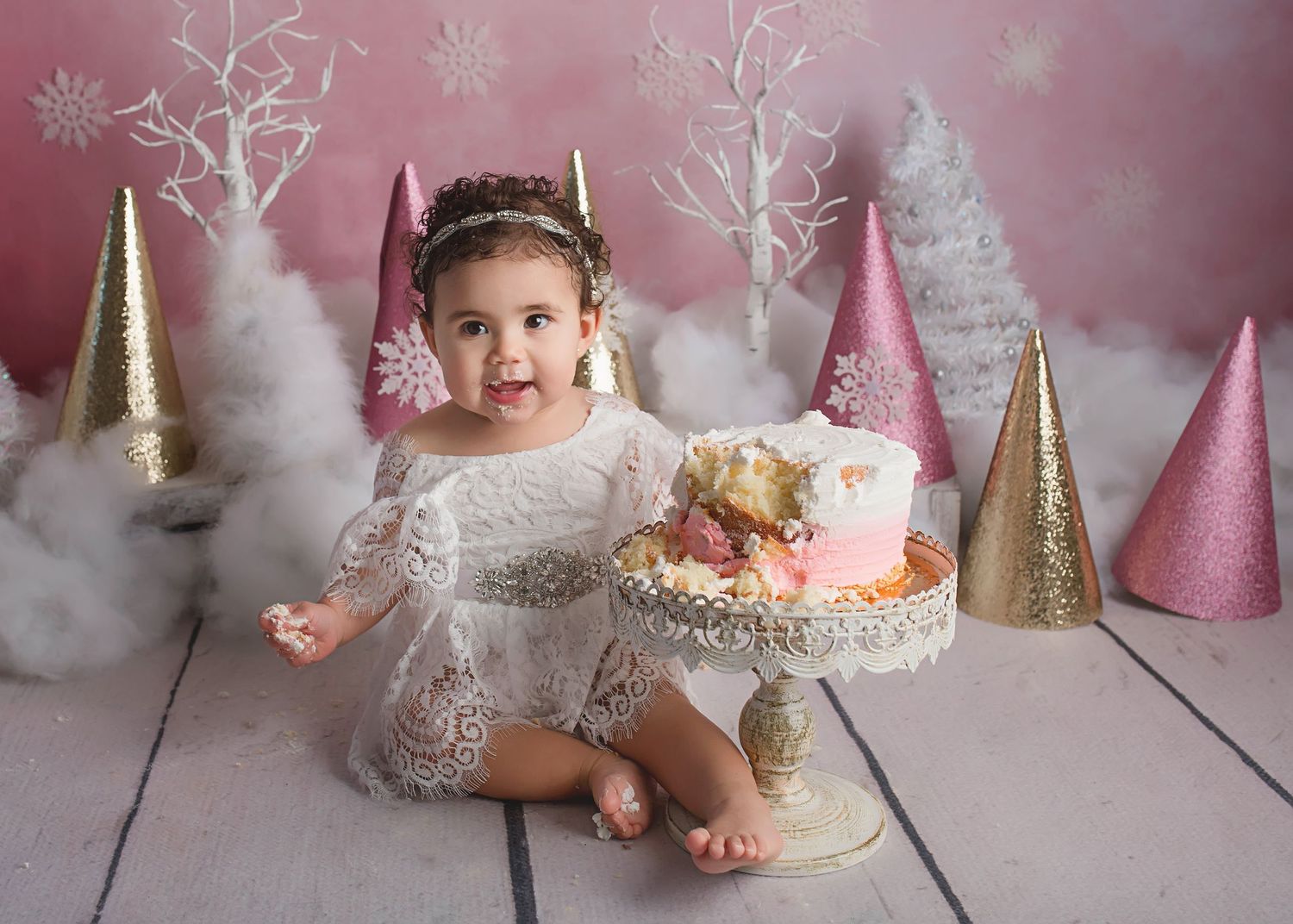 A decorated cake smash setup with pink and gold party decorations for a special celebration.
