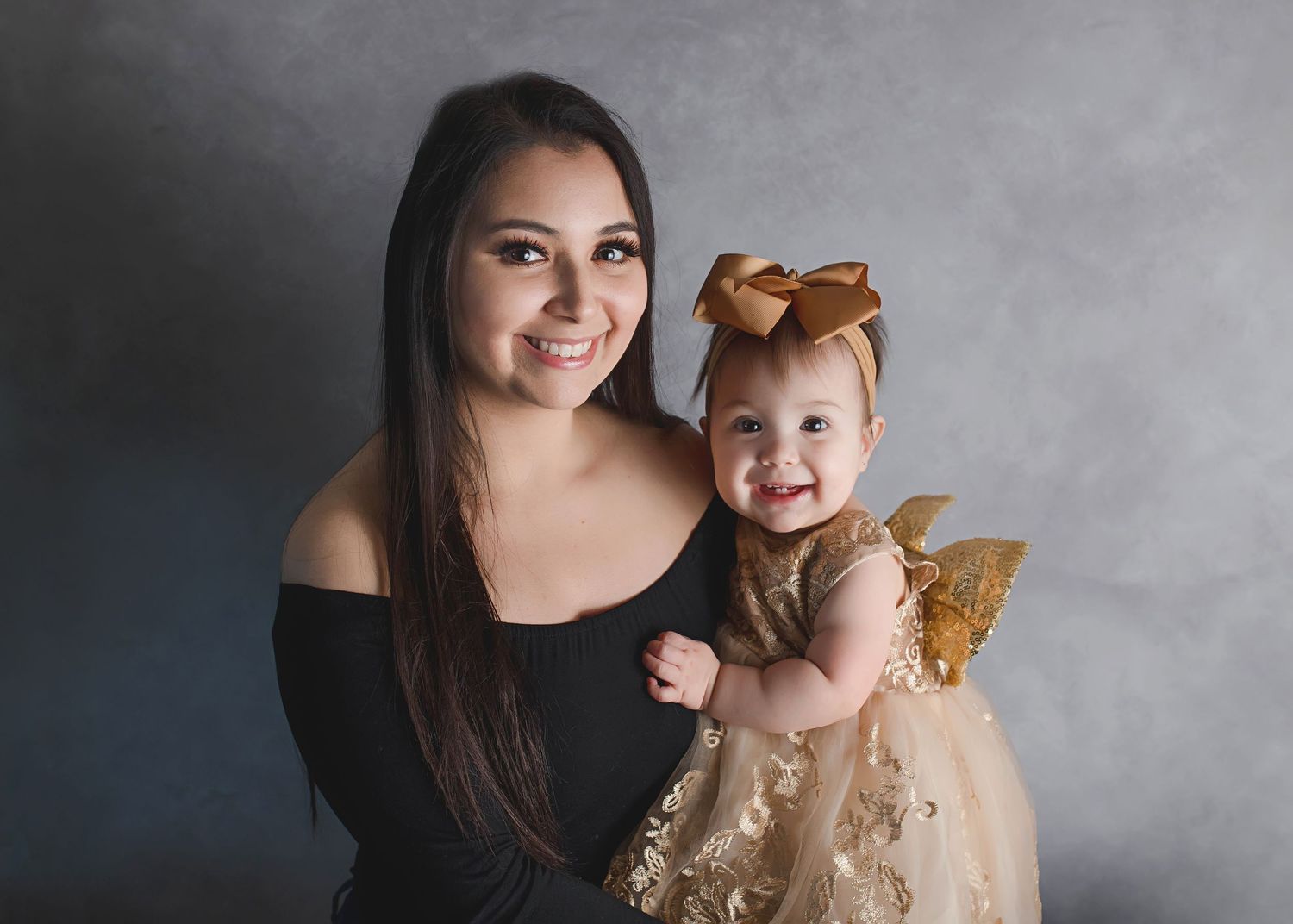 Sweet portrait session against grey backdrop with matching gold clothing.