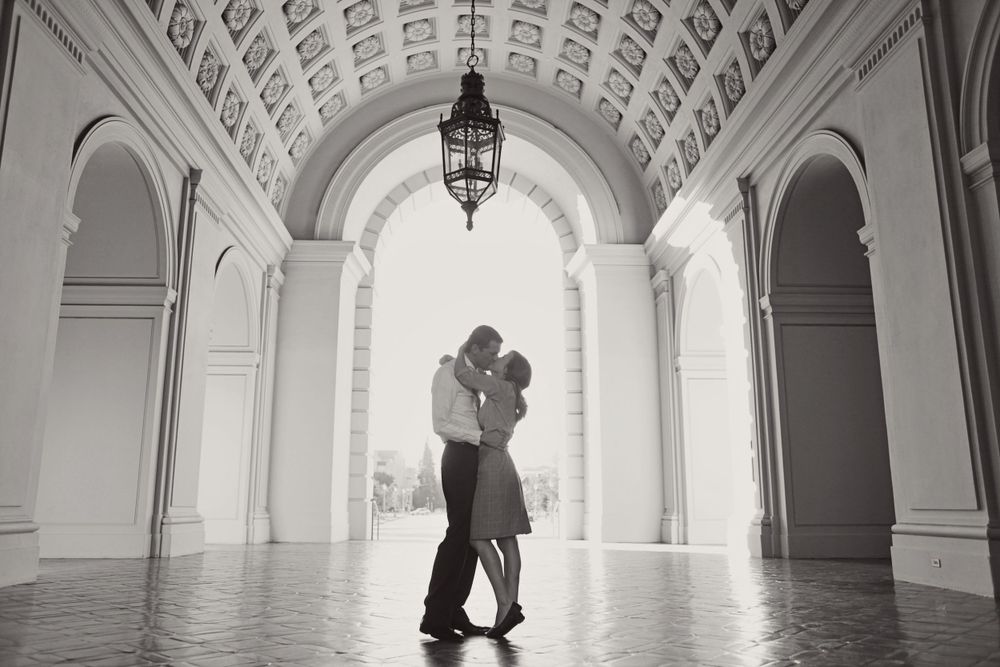 Romantic silhouette of couple embracing under grand architectural archway.