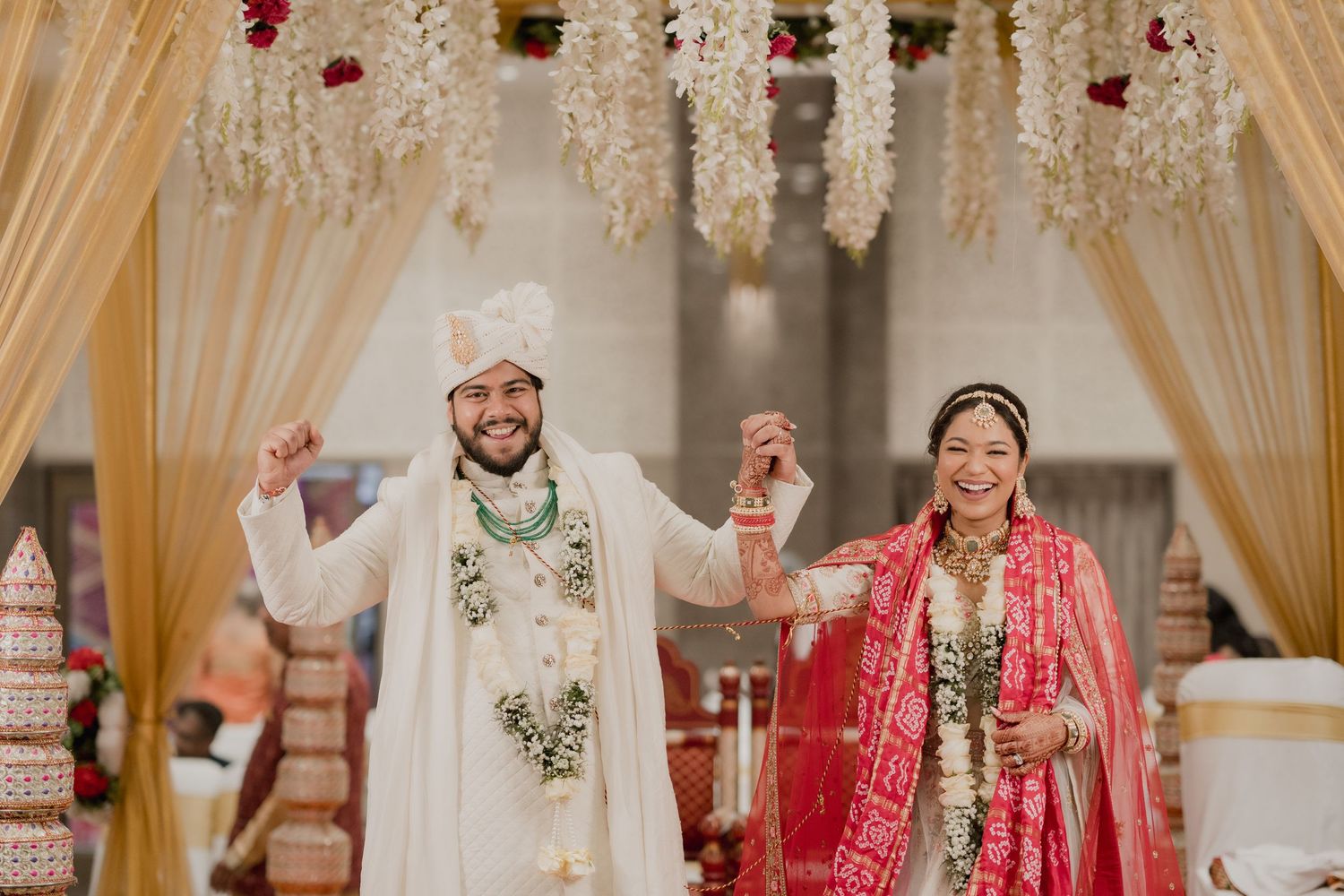 Traditional Indian wedding ceremony with decorative gold drapes and floral arrangements.