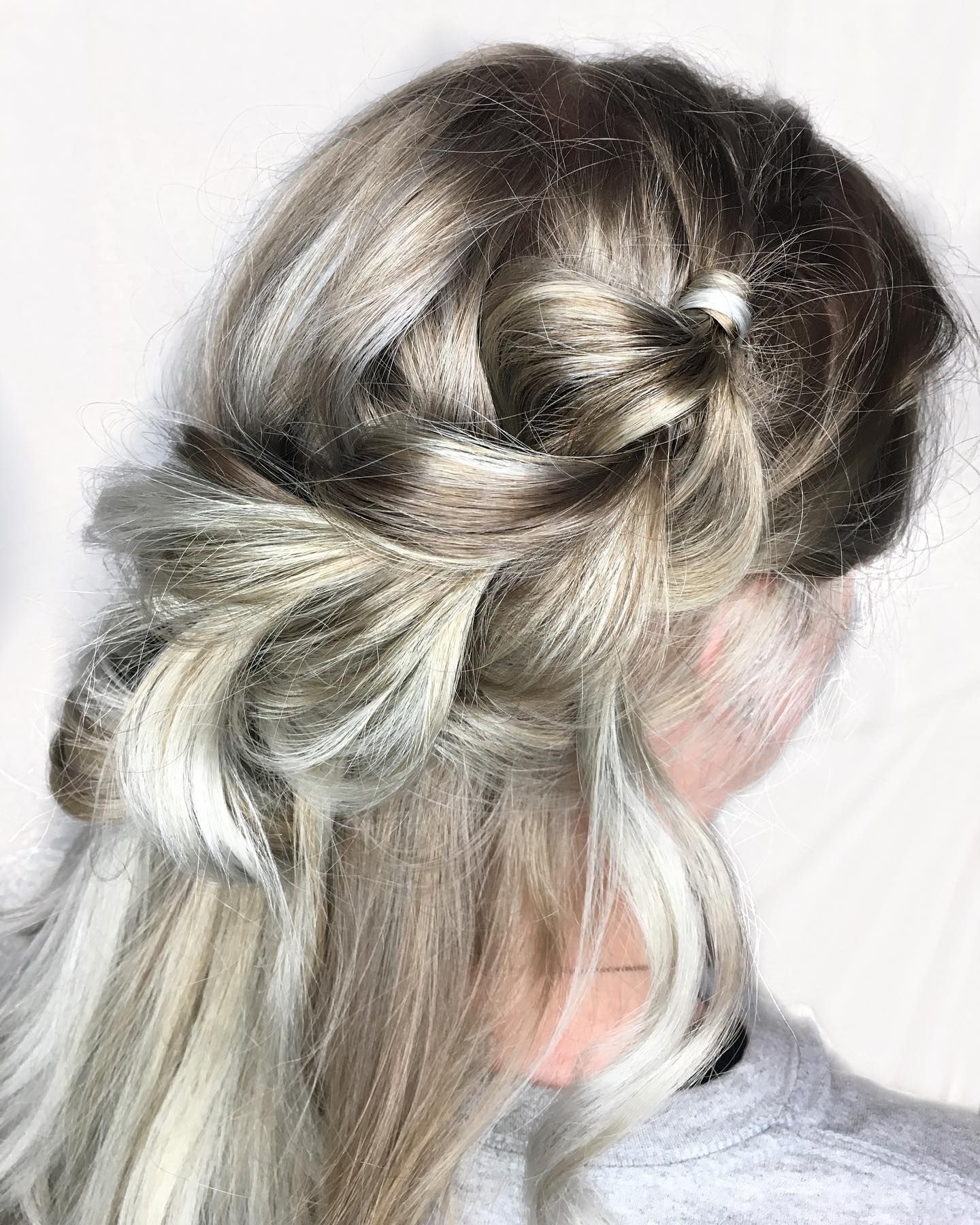 Elegant twisted updo hairstyle in platinum blonde with loose wisps framing the face.