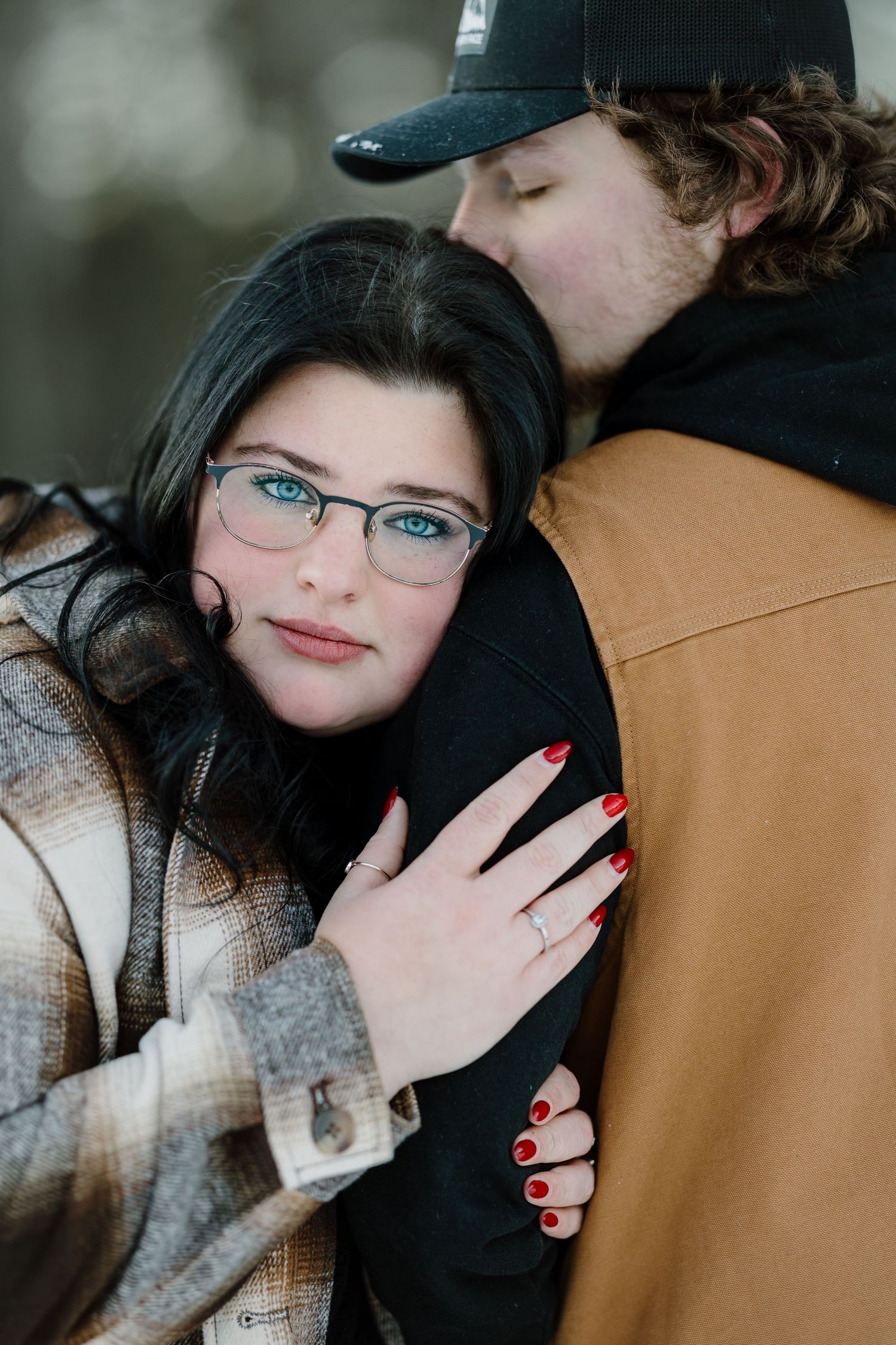 A tender winter engagement portrait showing a couple in cozy sweaters and jackets.