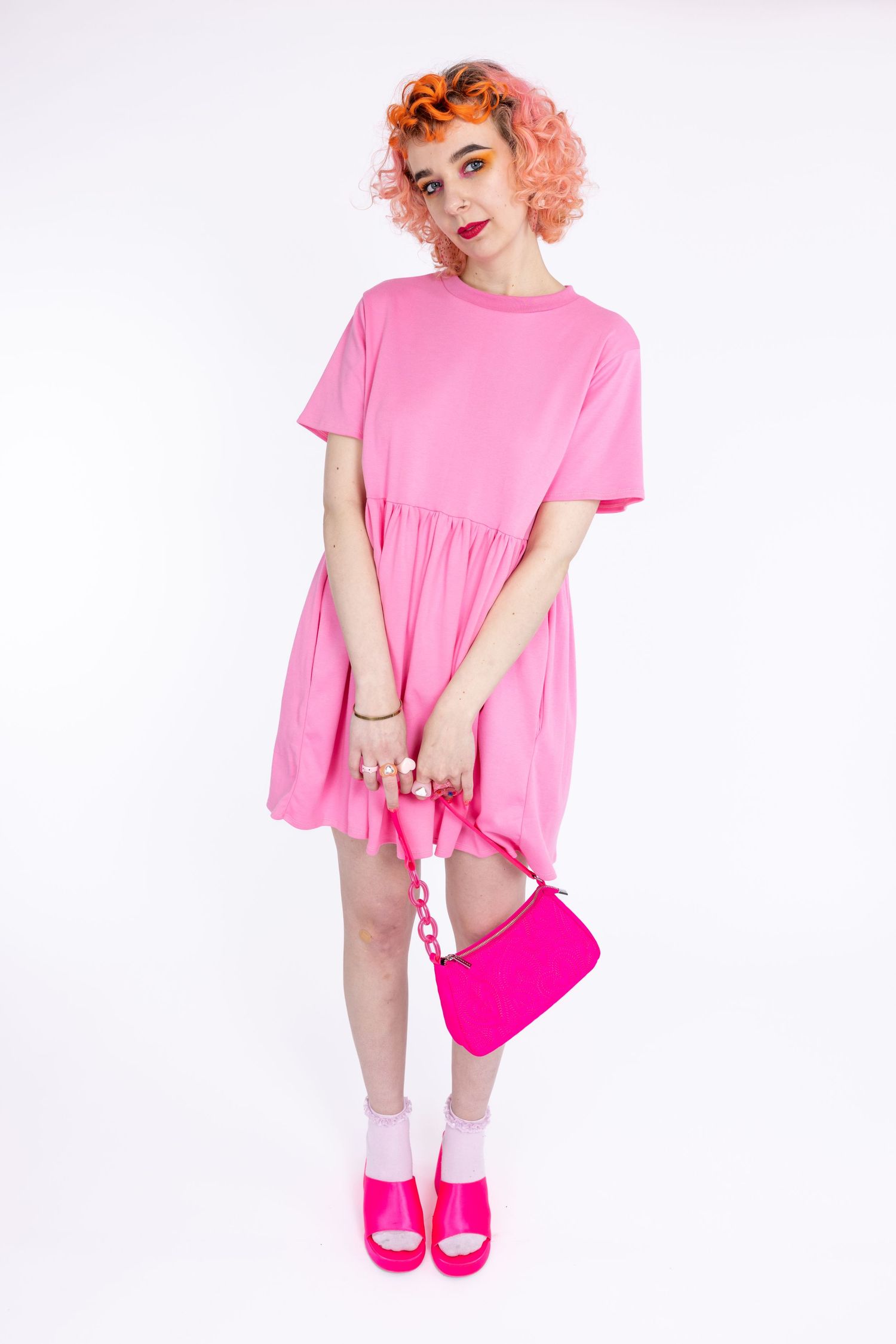 orange haired femme model wearing small business' Tallulah's Threads pink smock dress in a photography studio in Hove