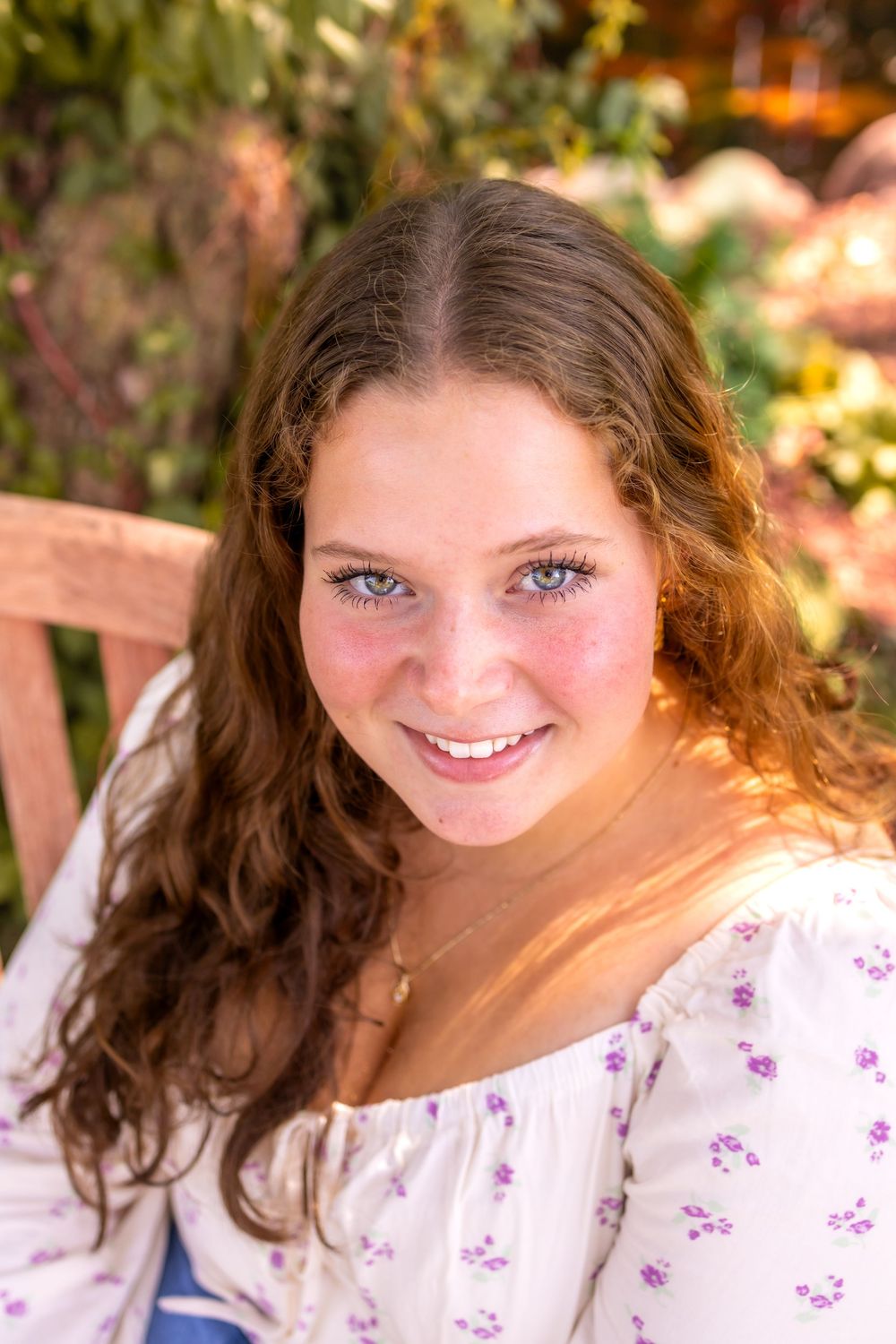 A person gives bright smiles in a series of warm outdoor portraits with sunlit bokeh and natural lighting effects.