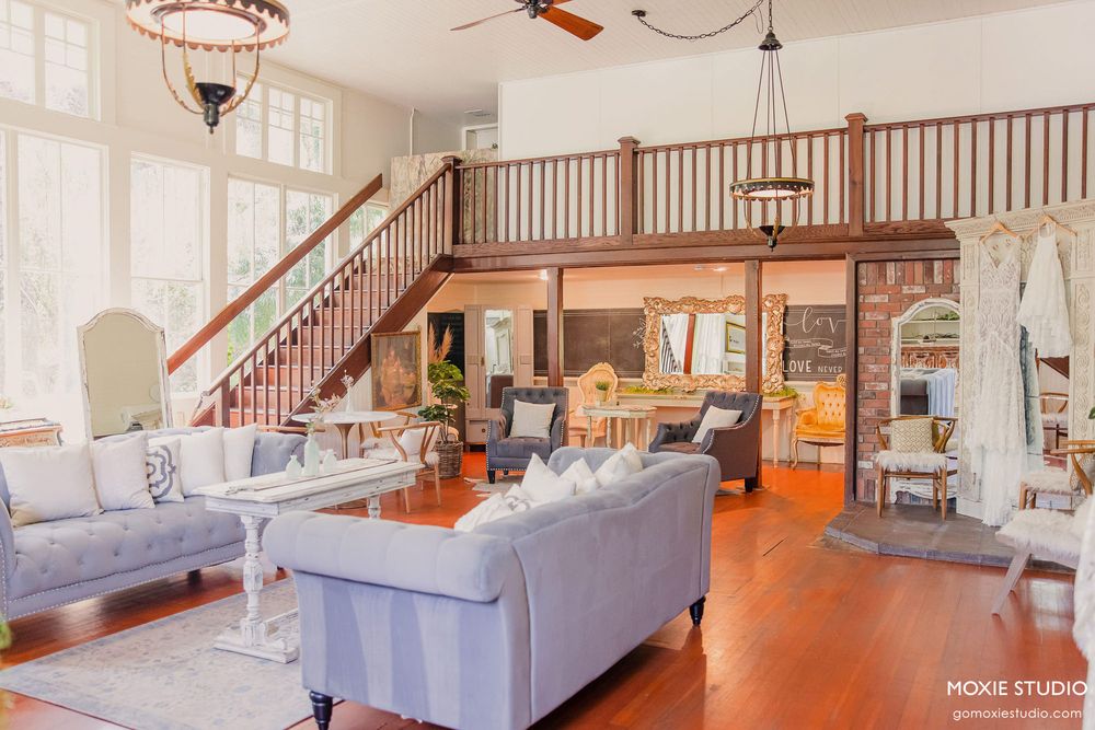 Panoramic view of an elegant indoor venue with hardwood floors, chandeliers, and a grand staircase.