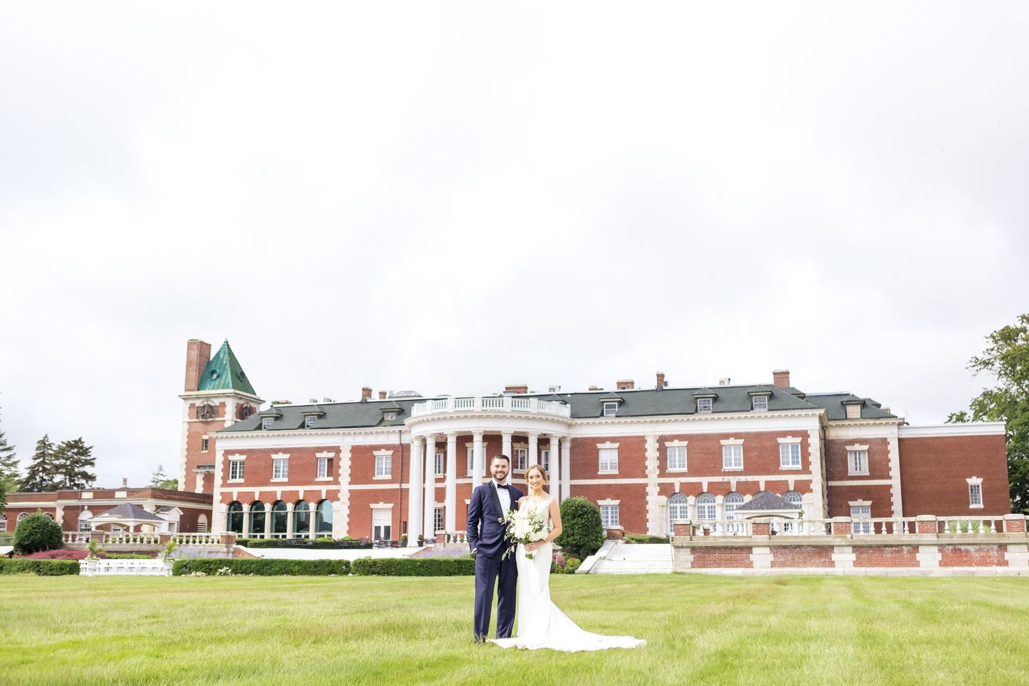 Elegant mansion wedding venue with large red brick building and manicured green lawn.