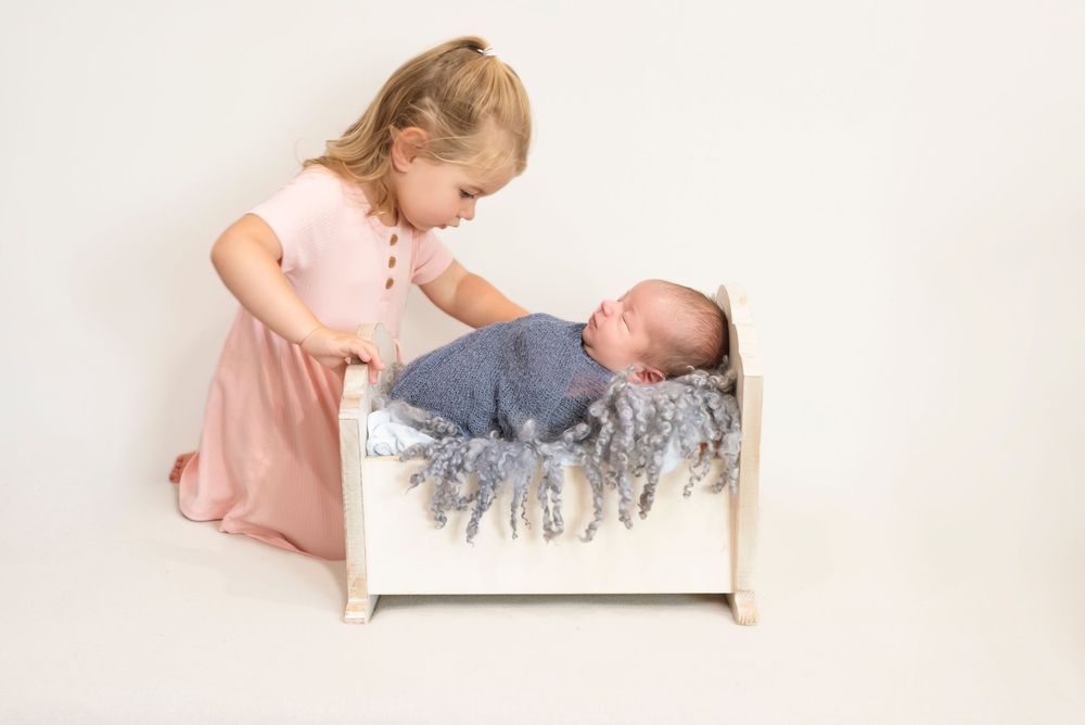 Siblings photoshoot. Proud big sister admiring her new baby brother as he is home from the Hospital. In home newborn shoot by Steph