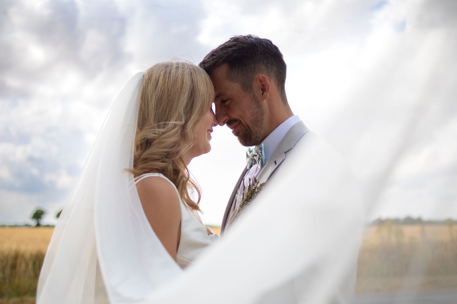 Bride and groom on wedding day under veil photograph