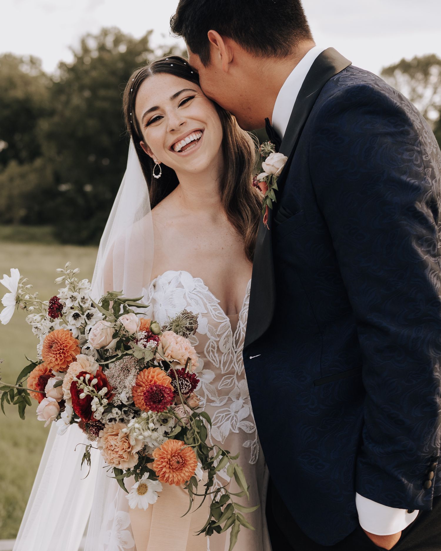 A joyful wedding moment with a beautiful autumn-toned floral bouquet of dahlias and roses.