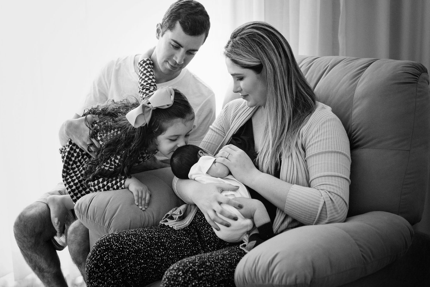 Family shares intimate moment together on couch with newborn.