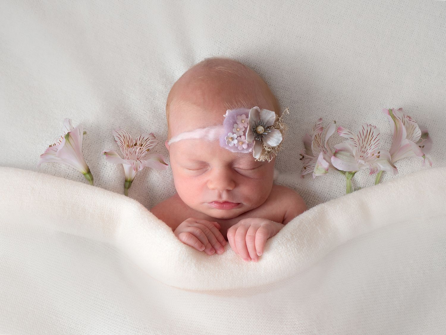 baby tucked in bed with fresh flowers either side