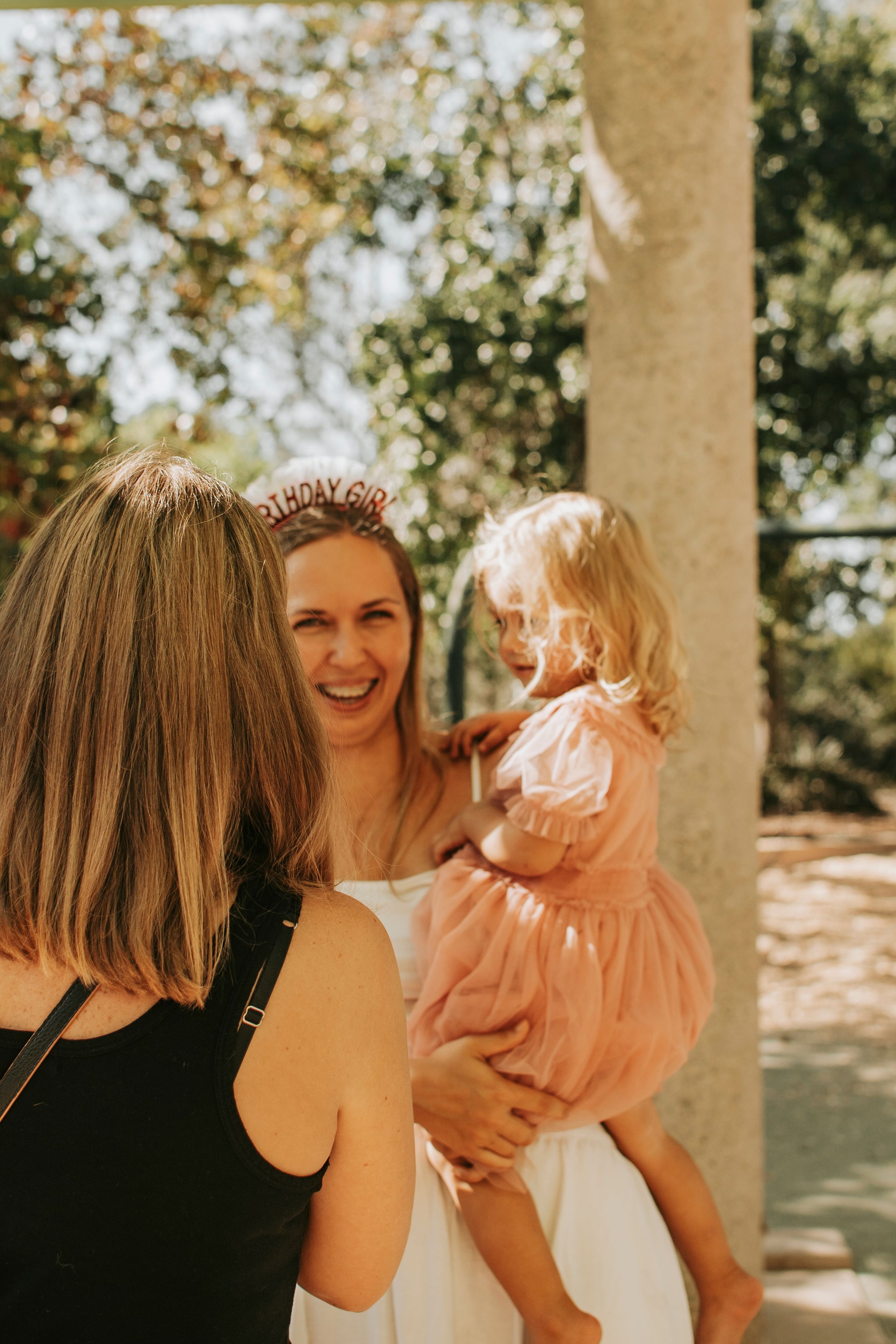 Friends sharing a joyful moment together under a covered porch area outdoors.