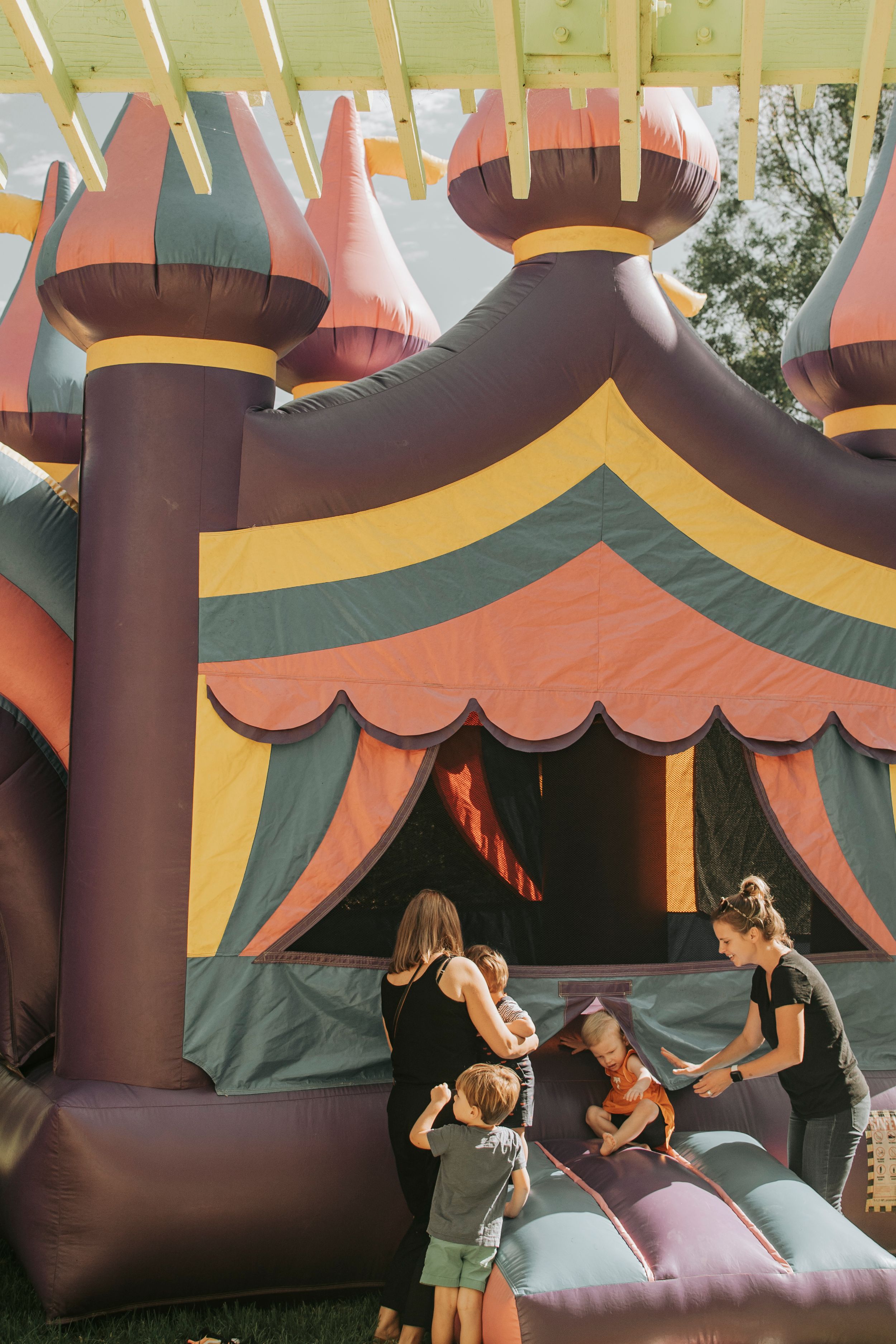Kids jumping and playing in a colorful inflatable bounce house at a party.