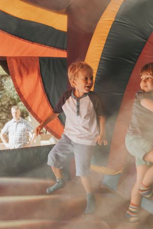 Children jumping and playing inside a colorful bounce house at an outdoor event.