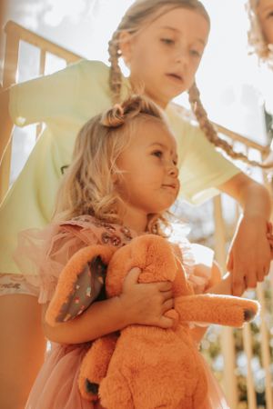 Two children sharing a tender moment while holding a stuffed animal toy.