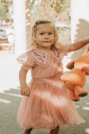 Child in pink tulle dress twirling and dancing at an outdoor party.