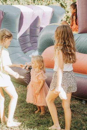 Three people playing near a large inflatable bounce house at an outdoor event.