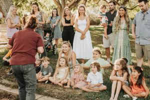 Large group gathering outdoors for casual photos under trees.