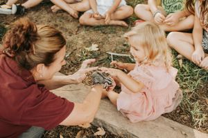 Children and adults gather on the ground during a fun outdoor activity in natural lighting.