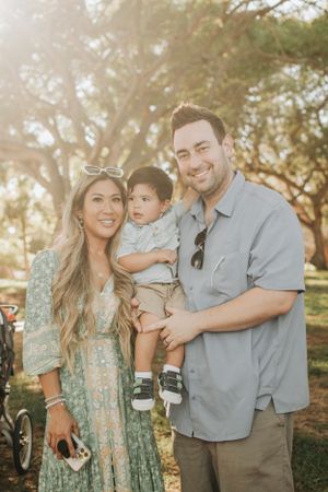 Family wearing coordinated outfits poses together in warm sunset lighting outdoors.