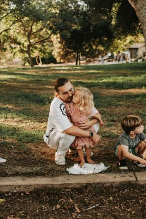 Intimate family moment captured at sunset in park setting.