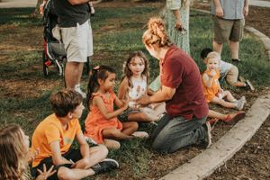 A group of children gather outdoors on a grassy area for an engaging activity.