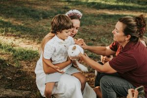 A tender moment shared between people sitting outdoors with a small white pet.