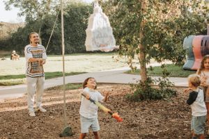 Children playing outdoors with a white decorative structure hanging in the background.