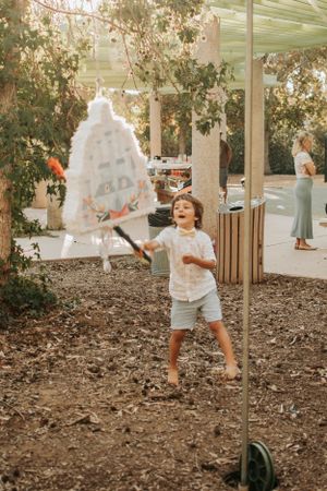 Child in white shirt playing under a hanging white decoration in an outdoor setting.