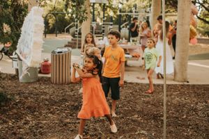 Children enjoying outdoor activities in orange and light colored outfits.