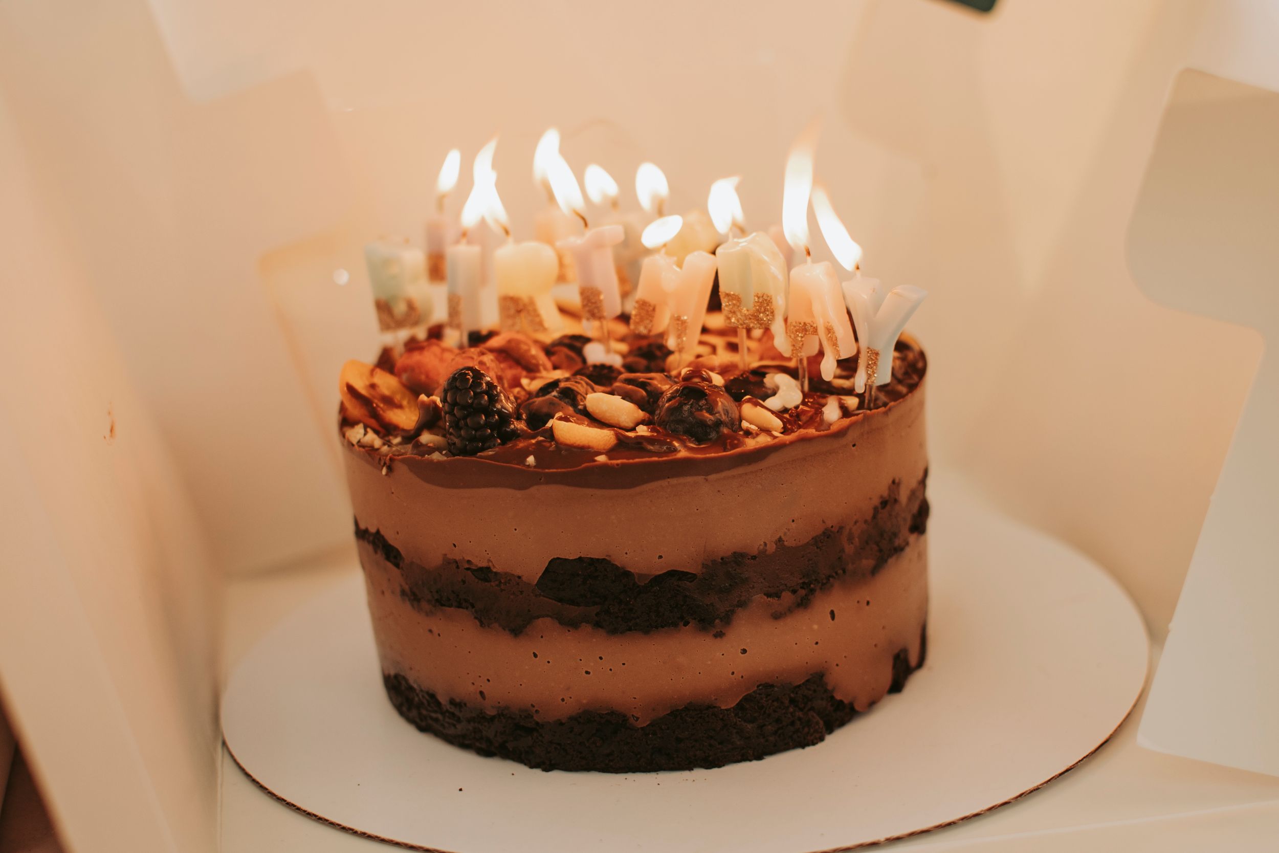 A chocolate dessert with candles glows warmly in low lighting.