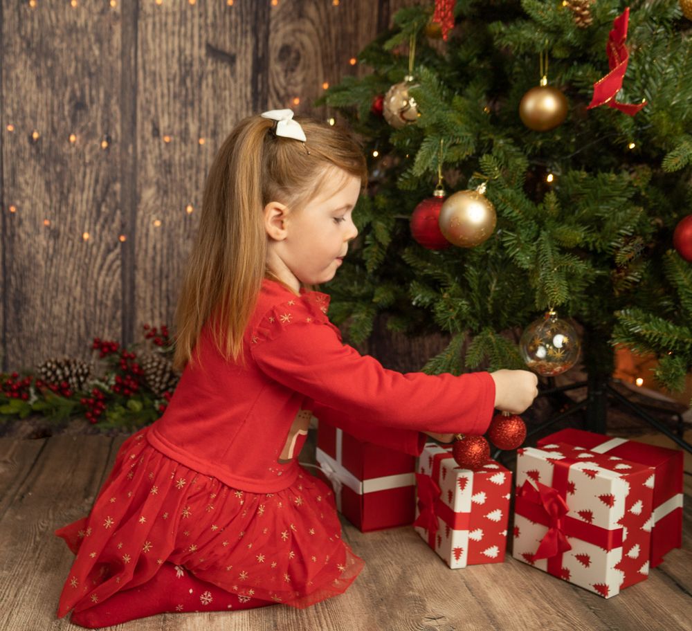 Little girl putting up bobbles on christmas tree
