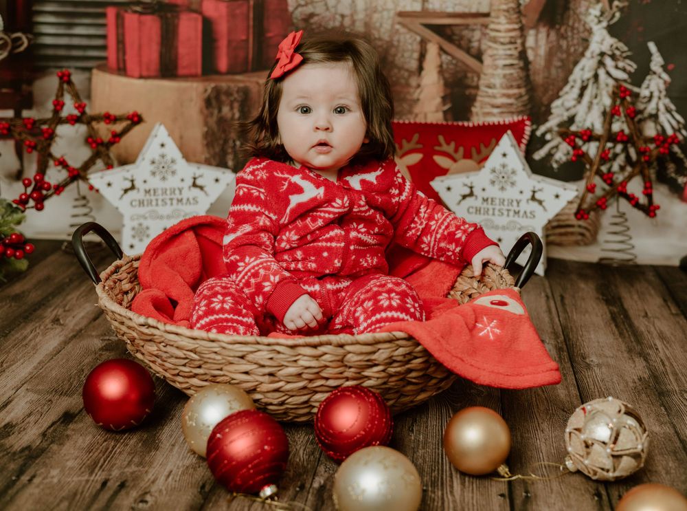 little girl in basket with Christmas bobbles around